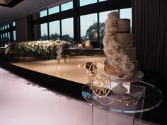 a wedding cake sitting on top of a table next to a large window with flowers