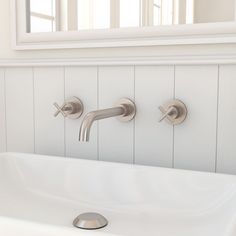 a bathroom sink with two faucets and a mirror in the back wall behind it