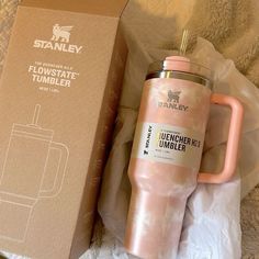 a pink coffee mug sitting next to a cardboard box on top of a white blanket