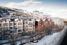 a group of buildings with snow on the ground and mountains in the backgroud