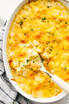 a large casserole dish with chicken and cheese in it on a striped cloth