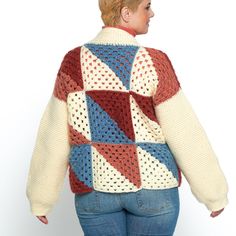 a woman wearing a multicolored sweater and jeans is looking back at the camera