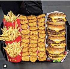 a tray filled with hamburgers and fries next to a container of chicken nuggies