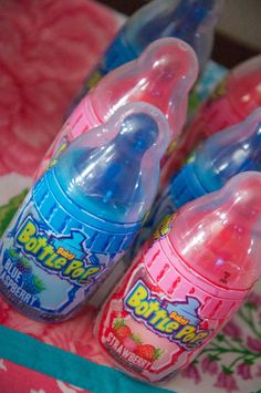 three baby bottles sitting on top of a pink and blue table cloth with flowers in the background