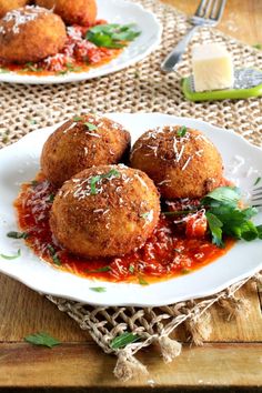 two white plates topped with meatballs covered in marinara sauce and parmesan cheese