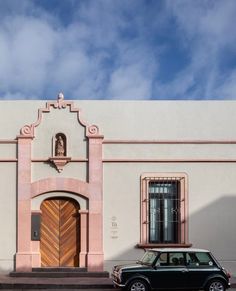 a car parked in front of a building with a door and window on the side