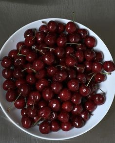 a white bowl filled with cherries on top of a table