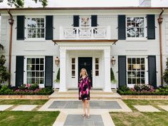 a woman standing in front of a white house