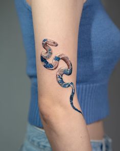 a woman's arm with a snake tattoo on the left side of her arm