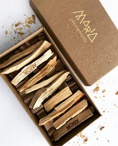 an open box filled with wooden sticks next to a cardboard box full of wood shavings