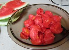 watermelon pieces are in a glass bowl next to sliced melon wedges