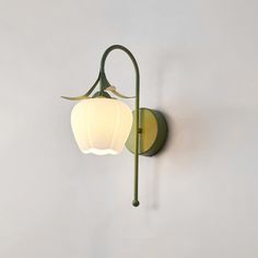 a green wall light with a white shade on the top and bottom part, hanging from it's side