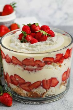 a cake with strawberries on top in a glass dish next to other desserts