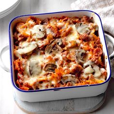 a casserole dish with meat, cheese and mushrooms in it on a table