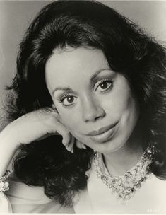 an old black and white photo of a woman with her hand on her chin looking at the camera