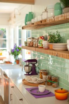 a kitchen with green tiles and shelves filled with dishes, cups, bowls and utensils