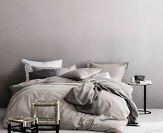 an unmade bed in a bedroom with grey walls and white carpeted flooring