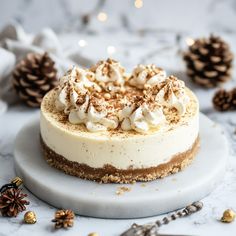 there is a cake with white frosting on the plate and pine cones around it