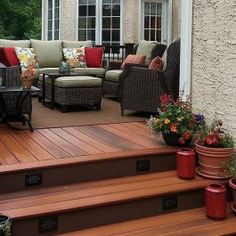 a deck with chairs, couches and potted plants on the side of it