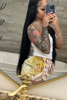 a woman taking a selfie in front of a mirror with long hair and tattoos on her arms