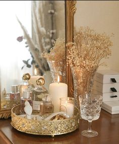 a table topped with candles and vases on top of a wooden table next to a mirror