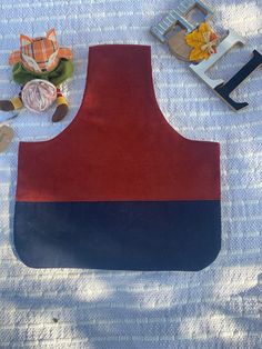 an apron made out of red, blue and black material next to toys on a bed