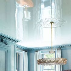 a dining room with blue walls and white curtains on the windowsills is shown