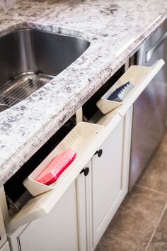 a kitchen counter with a sink and dishwasher in front of it that is open