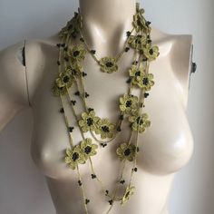 a mannequin wearing a yellow and black necklace with flowers on it's neck