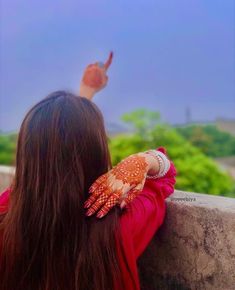 a woman with her hands on the back of her head, looking out at trees