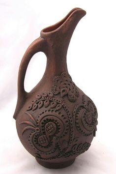 a brown vase with intricate designs on the outside and inside, sitting on a white surface