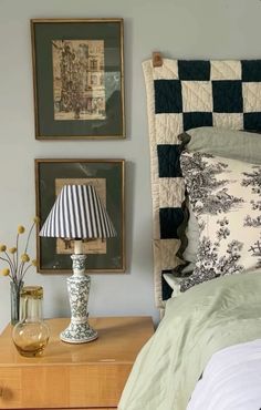 a bedroom with two pictures on the wall and a lamp in front of the bed