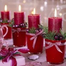 a table topped with red cups filled with candles and christmas decorations on top of it