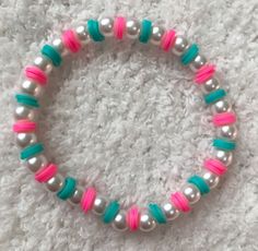 a close up of a bracelet with pearls and beads on a white carpeted surface