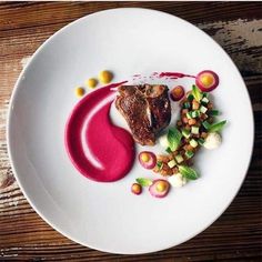 a white plate topped with meat and veggies on top of a wooden table