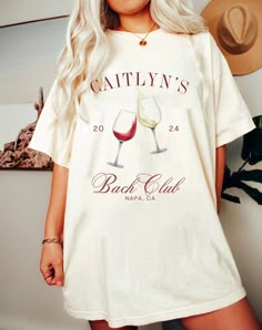 a woman standing in front of a wall wearing a t - shirt with two glasses of wine on it