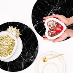 two plates with gold and white decorations on them, one is holding a piece of fruit