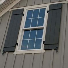 an open window on the side of a house with black shutters and white trim