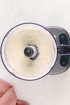 an overhead view of a food processor with white rice in it and someone's hand next to the blender