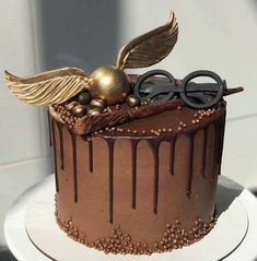 a chocolate cake with gold decorations and glasses on top is sitting on a white plate