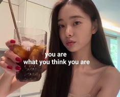 a woman holding up a glass filled with liquid