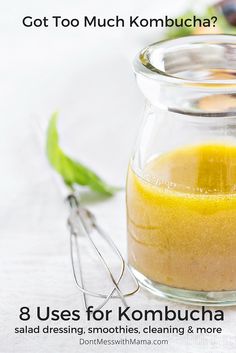 a glass jar filled with yellow liquid next to green leaves