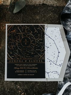 the wedding stationery was done in black and white with gold foil on it, along with an astro - themed pocketfold