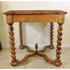 an old wooden table with turned legs and carved wood carvings on the top, sitting in a room next to a wall