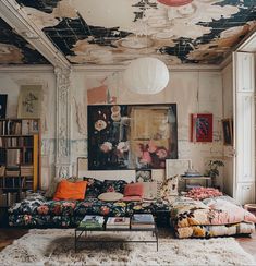 a living room filled with furniture and paintings on the wall above it's windows