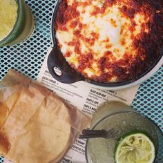 some food is sitting on top of a table next to drinks and paper napkins