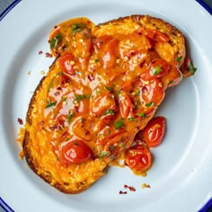 a piece of bread with tomatoes on it is sitting on a white and blue plate