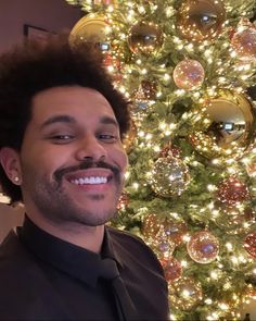 a smiling man in front of a christmas tree