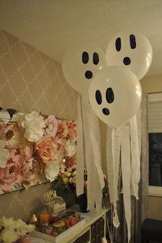 some balloons with faces on them are hanging from the ceiling in a room filled with flowers