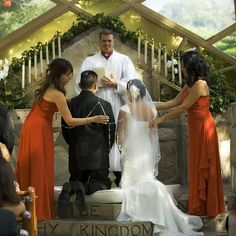 a group of people standing around each other in front of a man and woman at a wedding